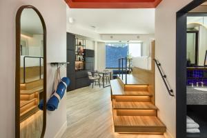 a living room and kitchen with stairs leading to the dining room at Catbird Hotel in Denver