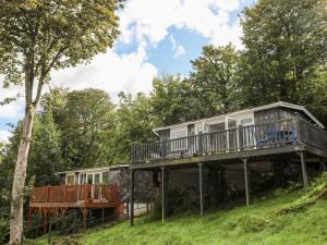 a house with a wrap around deck in the woods at Sundowner in Caernarfon