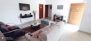 uma sala de estar com um sofá branco e uma televisão em Pousada Paraíso das Águas Capitólio em Capitólio
