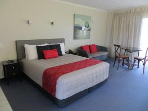 Harbour View Seaside Accommodation Napier في نابيير: غرفة فندقية بسرير وطاولة وكراسي