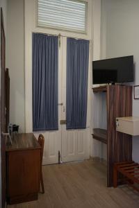 a room with a door with blue curtains and a tv at Hotel Principal in Mexico City