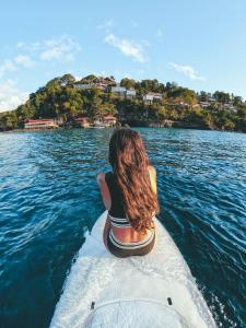 una mujer sentada en la parte trasera de un barco en el agua en Ti Kaye Resort & Spa en Anse La Raye