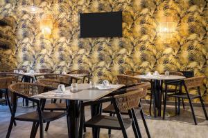 a dining room with tables and chairs and a wall at Best Western Plus Hôtel Belfort Centre Gare in Belfort