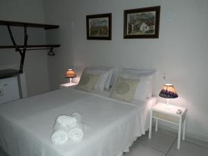 a bedroom with a white bed with two lamps at Pousada Casa de Maria Bonita in Arraial d'Ajuda