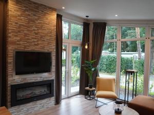 salon z kominkiem i telewizorem w obiekcie Nature-Connected Modern Stay w mieście Hoenderloo