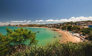 a beach with people and boats in the water at Casa Duplex Nova em Iriri in Iriri