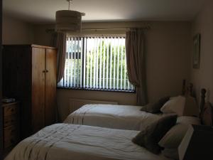 a bedroom with two beds and a window with a dresser at Firtrees Bed & Breakfast in Rostrevor