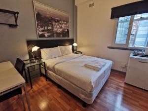 a bedroom with a bed and a desk and a window at City Centre Budget Hotel in Melbourne