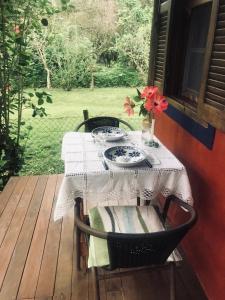 uma mesa com um vaso de flores sentado num alpendre em Cabana Lua - Praia de Castelhanos em Ilhabela