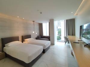 a hotel room with two beds and a flat screen tv at ashley hotel bkk in Bangkok