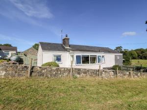 une maison blanche derrière une clôture en pierre dans l'établissement Berth, à Pwllheli