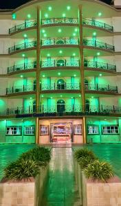 ein großes Gebäude mit grüner Beleuchtung und Pflanzen davor in der Unterkunft Al Mansour Grand Hotel in Hafar Al-Batin