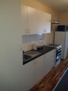 a kitchen with white cabinets and a sink and a refrigerator at Whyalla Country Inn Motel in Whyalla