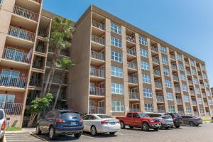 a large apartment building with cars parked in a parking lot at Charming 1 Bedroom, 3 Minute Walk To The Beach Condo in South Padre Island