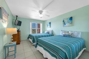 two beds in a room with blue walls at Charming 1 Bedroom, 3 Minute Walk To The Beach Condo in South Padre Island
