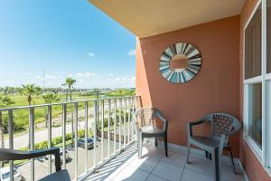 a balcony with chairs and a view of a street at Charming 1 Bedroom, 3 Minute Walk To The Beach Condo in South Padre Island