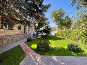 un cortile con prato verde e alberi e un edificio di Гостевой дом Шумкар Азия Guest House Shumkar Asia a Bishkek