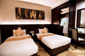 um quarto de hotel com duas camas e uma cadeira em Amansari Residence Resort em Johor Bahru