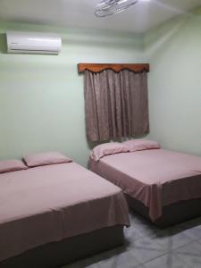 zwei Betten in einem Zimmer mit Fenster in der Unterkunft CASA CON TODO LOS SERVICIOS Y 2 RECAMARAS CLIMATIZADAS CON 2 CAMAS CADA UNO PARA 8 PERSONAs in Tecolutla