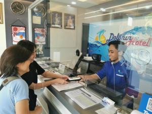a man and a woman standing at a cash register at Dolphin Hotel in Klang