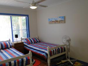 a bedroom with two beds and a fan and a window at Copacabana 2 cute unit with water views from the balcony in Corlette
