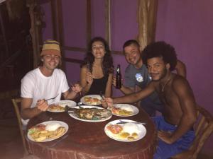 a group of people sitting around a table eating food at Bananas Guest House Private Room in Altagracia