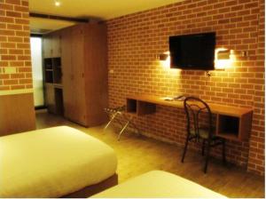 a bedroom with a bed and a desk with a tv at Bourbon St. Boutique Hotel in Bangkok