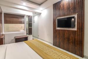 a bedroom with a bed and a tv on a wall at De Falcon Goa Beach Resort in Candolim