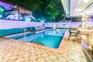 a swimming pool with a table and chairs next to it at De Falcon Goa Beach Resort in Candolim