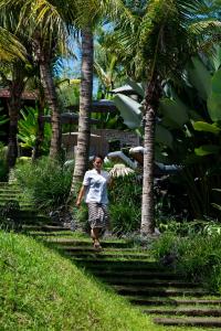 a man walking down a path between palm trees at Kalapa Boutique Resort & Yoga in Canggu