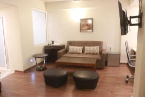 a living room with a couch and two ottoman at Hotel Starline in Guwahati