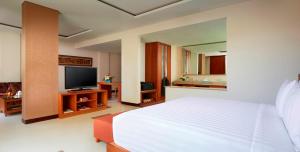 a bedroom with a white bed and a flat screen tv at Sun Island Hotel & Spa Legian in Legian