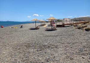 a beach with chairs and umbrellas and the ocean at Xristinas Seaside Apartments in Kolymvari
