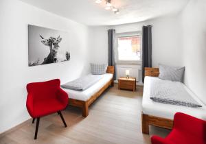 a room with two beds and a red chair at 8peaks in Pfronten