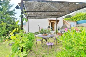 a patio with a table and chairs under a pergola at La Maison De Noelie - stunning house for rent in Le Bar-sur-Loup