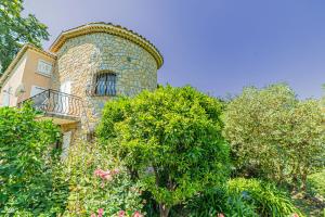a stone building with a balcony and some trees at Listed Accomodation 4 At 300m river 800m village and 30mn Nice Cannes Antibes in Le Bar-sur-Loup