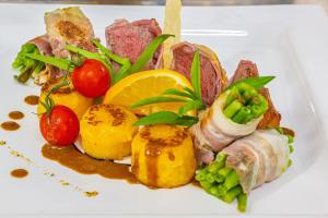 un piatto bianco di alimenti con carne e verdure di City Hotel Suhl a Suhl