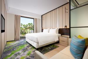 a bedroom with a white bed and a large window at Holiday Inn Bali Sanur, an IHG Hotel in Sanur