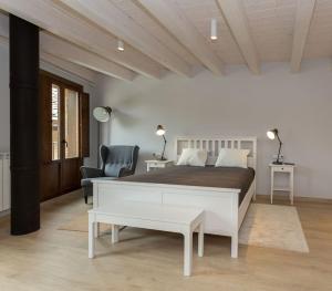 een witte slaapkamer met een bed en een stoel bij La Casa de los Mil Años in Estella