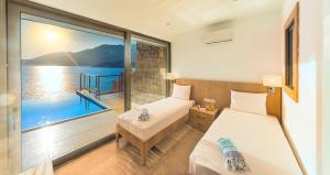 two beds in a room with a view of the water at Mekvin Hotels Deniz Feneri Lighthouse in Kaş