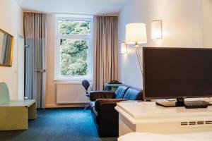 um quarto de hotel com uma televisão de ecrã plano num quarto em Hotel Benther Berg em Ronnenberg