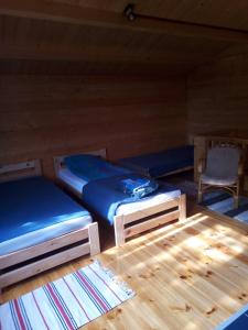 two beds in a room with a table and a chair at Dom Pod Sosnami in Lidzbark