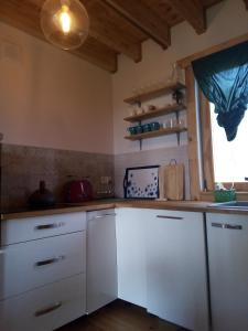 kuchnia z białymi szafkami i oknem w obiekcie Dom Pod Sosnami w mieście Lidzbark