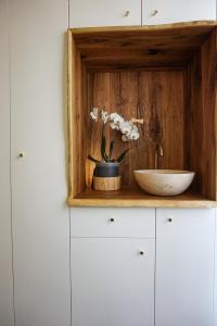 a wooden shelf with a bowl and flowers on it at #outofboxproject tiny-home and garden house in Timişoara