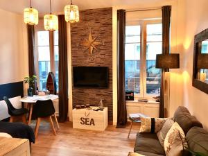 een woonkamer met een bank en een tv aan een bakstenen muur bij Cherbourg Sea Sand in Cherbourg en Cotentin