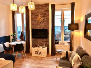 a living room with a couch and a tv on a brick wall at Cherbourg Sea Sand in Cherbourg en Cotentin