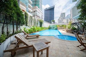 a swimming pool with two chairs and a table at Hotel Mermaid Bangkok in Bangkok