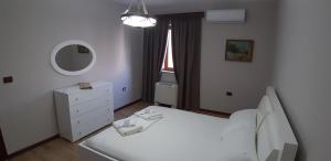 - une chambre avec un lit blanc et un miroir dans l'établissement Stela's Apartment, à Korçë