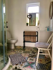 a bathroom with a toilet and a chair and a window at Ballygally Seaview and Garden Hideaway in Ballygalley