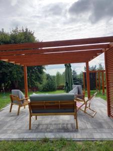 a pavilion with a bench and chairs on a patio at Dom Pod Sosnami in Lidzbark